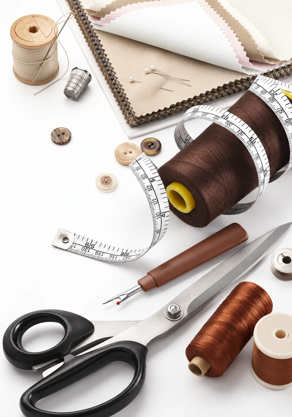 Tailor's shears, thread, tape measure, buttons and fabric swatches on a workbench