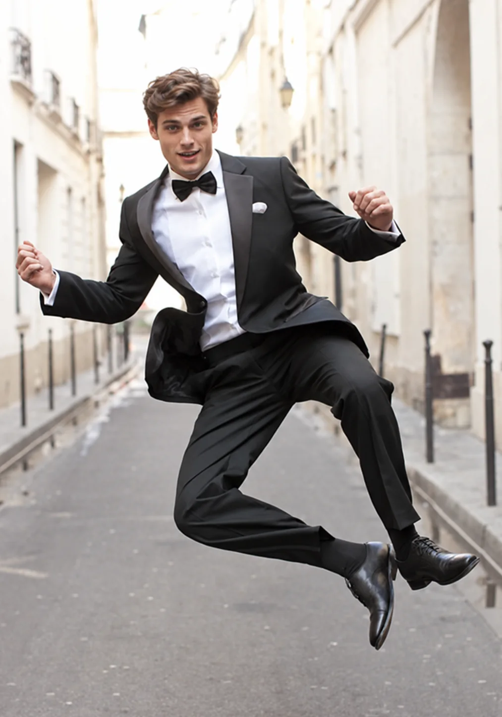 A man in a fitted black tuxedo and bow tie, mid-stride
